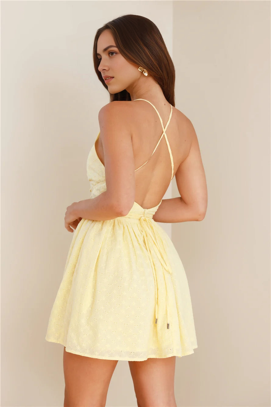 A light yellow camisole short dress with a deep V-neckline and lace up design. The skirt has exquisite hollowed out textures that are suitable for dates, vacations, and more