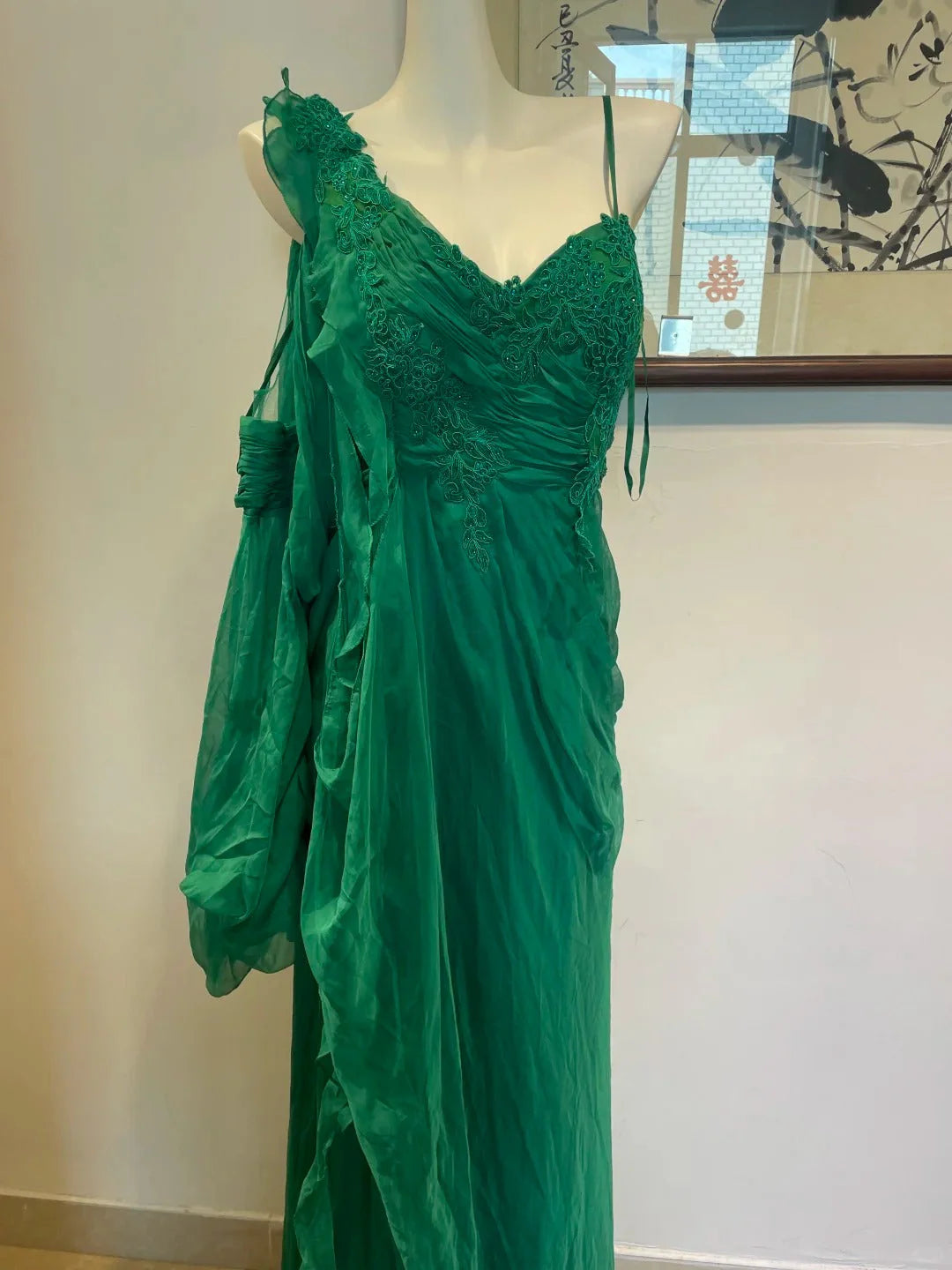 Dark green dress, made of lightweight yarn fabric, with a deep V-neck and asymmetrical floating sleeves